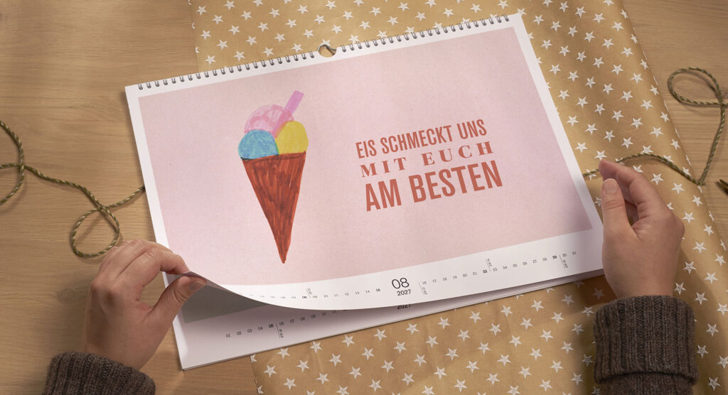 Eine Person blättert durch einen Kalender mit einem bunten Meeresfrüchte-Eis auf der Seite.